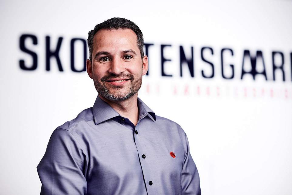 Anders-Skorstensgaard-med-dk-kort-i-baggrunden-smiler