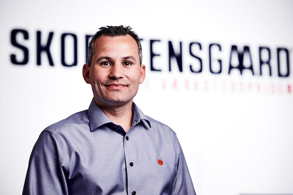 Martin-skorstensgaard-med-dk-kort-i-baggrunden-smiler